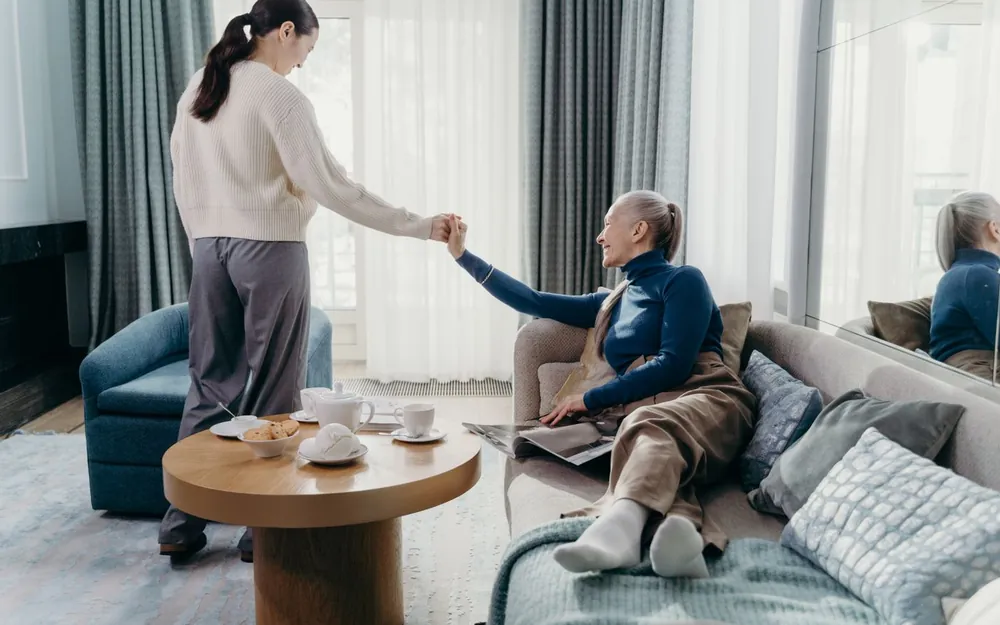 An adult child and an aging parent talking in a bright living room