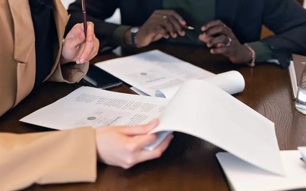 Hands reviewing documents together at a warm wooden table